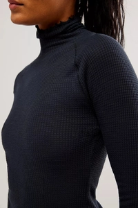 Close-up of black waffle knit texture with elegant ruffle edges on high neck and sleeve cuffs