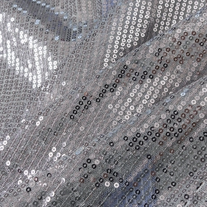 Gros plan de paillettes argentées sur tissu mesh montrant la texture et les détails