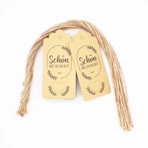 Detail of kraft paper gift tags with German text and natural jute rope on white background