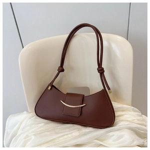 Detail of a brown matte leather crescent bag with a gold curved metal buckle closure