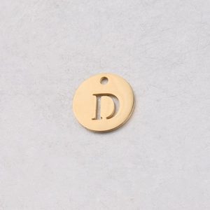 Détail macro d'un pendentif rond doré de 12mm avec lettre D en acier inoxydable poli