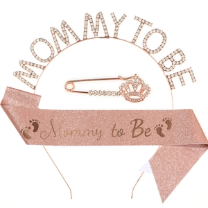 Close-up of rose gold Mommy To Be rhinestone tiara, pink glitter sash and crown pin