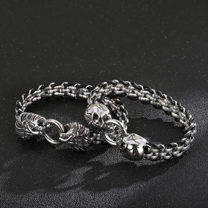 Detail of stainless steel lion head and skull charm bracelets with black woven rope