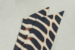 Détail d'un foulard twilly étroit à motif girafe avec des extrémités pointues élégantes