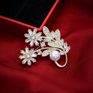 Elegant gold flower brooch with crystals and a large white pearl on red silk fabric