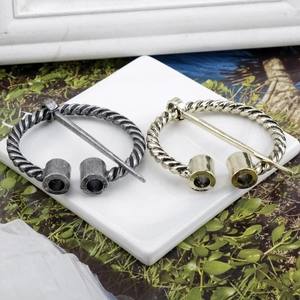 Detail of vintage Viking metal brooches in antique silver and gold with twisted texture