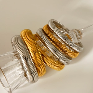 Elegant gold and silver stacked elastic snake chain bracelets on a glass stem display