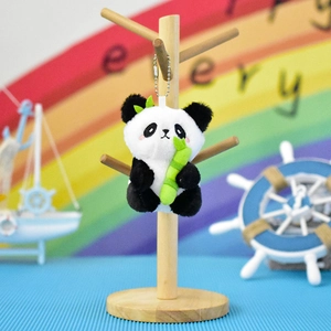 Detailed view of a cute plush panda keychain holding a bamboo stalk on a display stand.