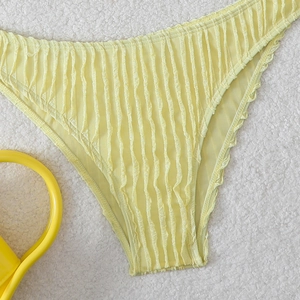Detail of yellow smocked bikini bottom fabric texture on white plush background