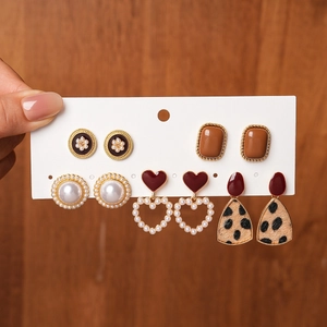 Detailed view of six vintage pearl and resin earring pairs on a display card