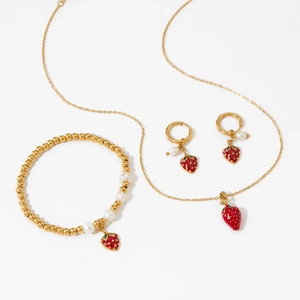Schmuckset aus goldenem Edelstahl mit roten Erdbeeren und weißen Perlen auf weißem Hintergrund