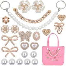 Flat lay of pink mini bag charm with pearl strap and assorted gold alloy brooches