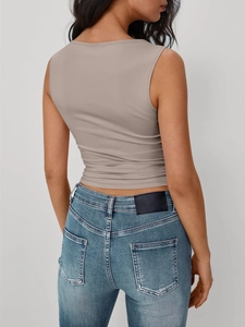Vista posteriore del top senza maniche taupe aderente con jeans in denim lavato blu