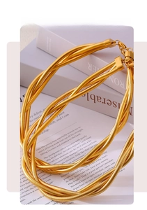 Macro detail of multi-strand gold snake chain necklace with lobster clasp on vintage book