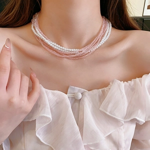 Detail of multi-layer necklace with pink crystal beads and white pearls on neckline