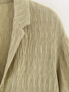 Détail du tissu texturé et du col à revers sur un blazer élégant de couleur vert sauge