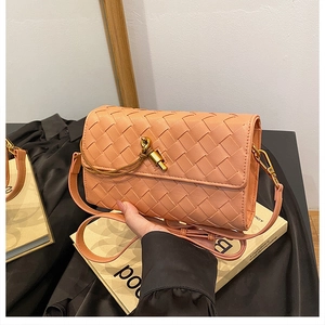 Detail of hand-woven crossbody bag in dusty rose with a golden knot clasp and leather strap