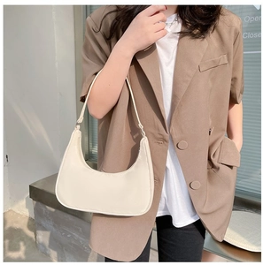 Minimalist cream white crescent shoulder bag shown on model with chic brown blazer