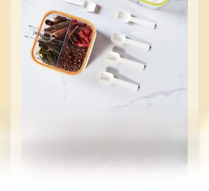 Close-up of four-compartment spice box with orange seals and four white plastic spoons