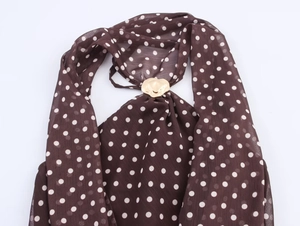 Détail du haut dos nu marron à pois avec une boucle métallique dorée en forme de cœur