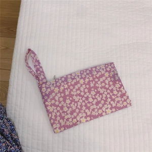 Détail de la pochette florale violette avec motifs marguerites et dragonne zippée