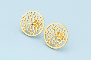 Detail of gold hollow floral stud earrings with white crystal center on blue background