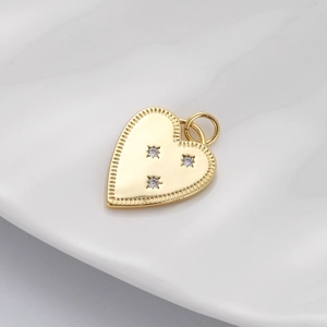 Detailed view of a gold heart pendant with zircon stones on a white ceramic plate