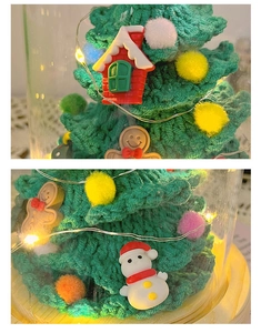 Detailed view of hand-knitted green Christmas tree with LED lights in a glass dome