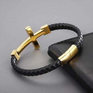 Detail of woven black leather bracelet with golden cross charm and magnetic clasp