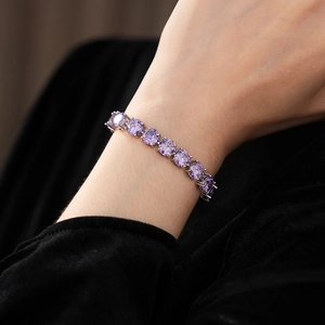 Macro detail of a sparkling purple zircon tennis bracelet on wrist with claw setting