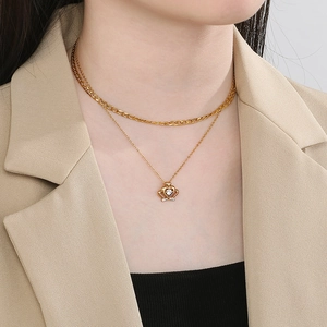 Detail of a gold double-layer necklace featuring a crown pendant with sparkling zircons