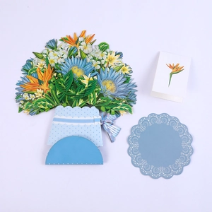 Macro detail of 3D pop-up bouquet card with blue Protea and orange Bird of Paradise flowers