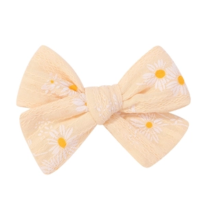 Nahaufnahme der beigen Schleifen-Haarspange mit Gänseblümchen-Print und Stofftextur
