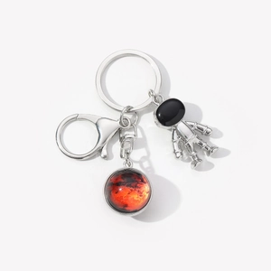 Detail of silver astronaut keychain with a red Mars glass pendant and metal clasp