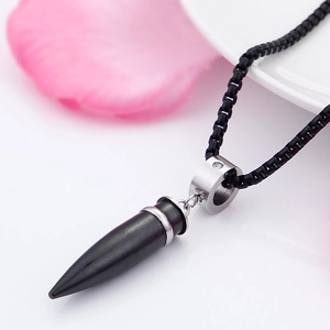 Macro view of bullet pendant necklace in silver and black on a floral white background