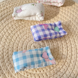 Close-up of floral and plaid fabric cable organizers with cute heart buttons on a mat