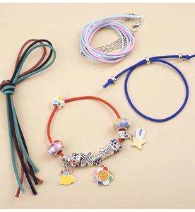Detail view of DIY jewelry set with colorful cords and enamel charms on beige background