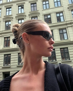 Close-up of black narrow frame sunglasses and minimalist silver earrings for street style