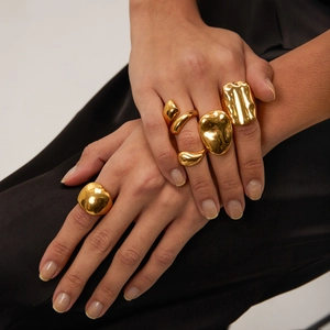 Dettaglio degli anelli spessi irregolari placcati oro 18 carati sulla mano della modella