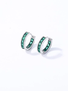 Detalle de pendientes huggie de plata con piedras verdes de corte cuadrado engastadas