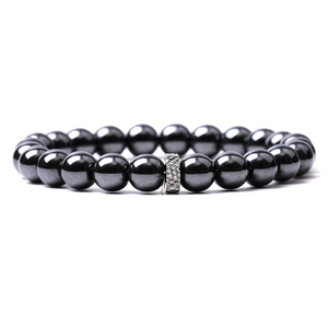 Detail view of tiger eye beads with silver rhombus engraved metallic charm on bracelet