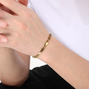 Détail d'un bracelet en acier inoxydable doré à maillons carrés sur le poignet d'un mannequin