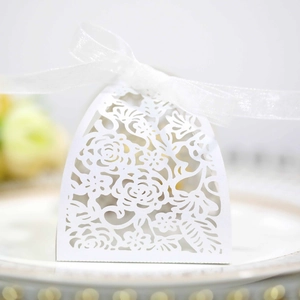 Detail of white laser-cut wedding favor box with floral patterns and a silk ribbon