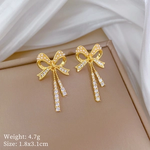 Detailed macro view of golden bow earrings with pearls and rhinestones on silk