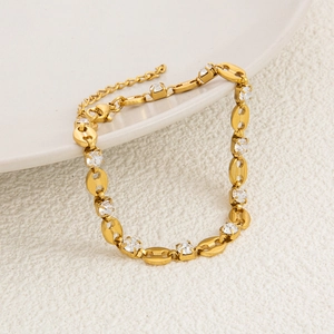 Close-up of gold 18K plated bracelet with coffee bean links and zircon stones on ceramic