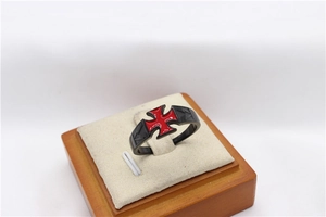 Detail of a black steel men's ring with a red iron cross inlay in a wooden gift box