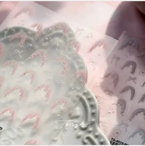 Detail of pink lace bow nail stickers with star patterns on white textured ceramic