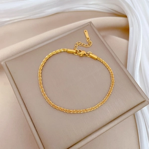 Minimalist titanium steel gold link chain bracelet displayed on a beige jewelry cushion