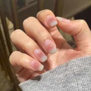 Close-up of short square-oval press-on nails with pink blush gradient and glossy finish