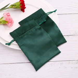Detailed close-up of dark green velvet drawstring jewelry pouches on a wooden table